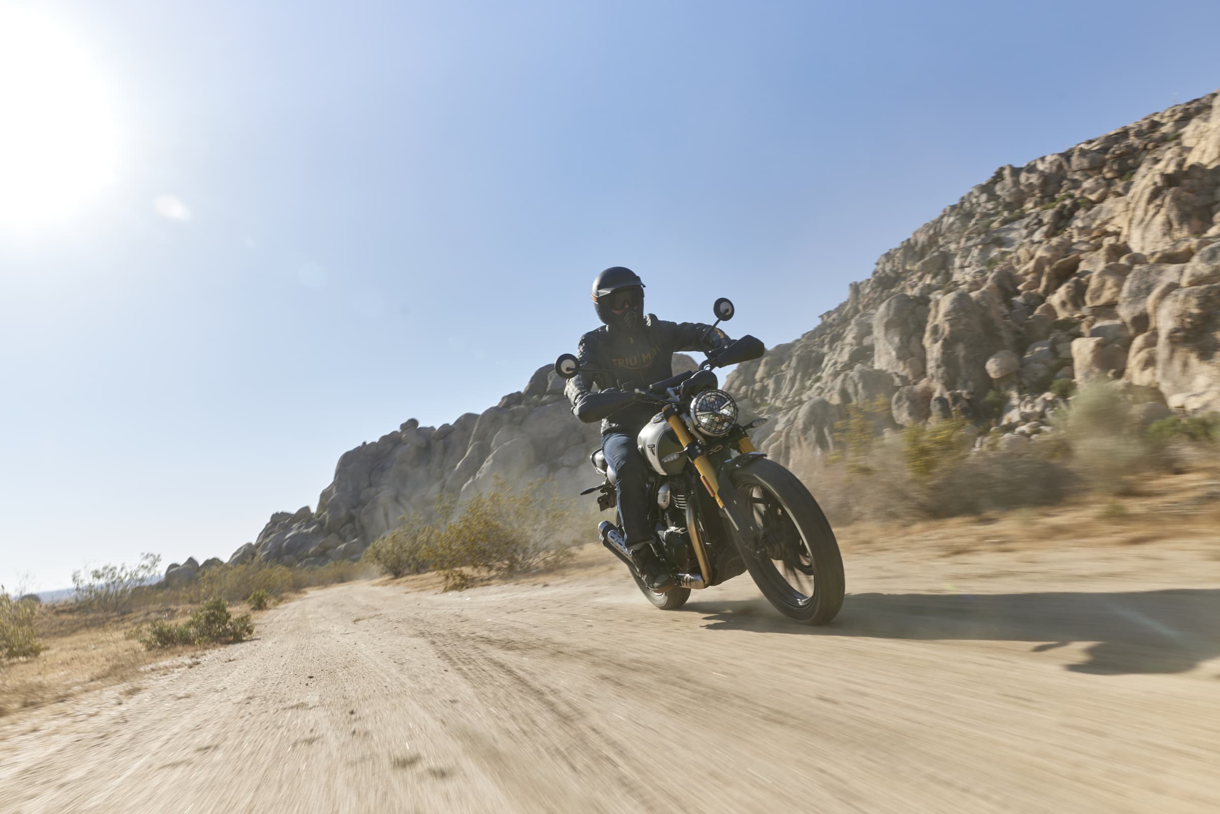 Triumph Scrambler 400 X riding on a sandy road